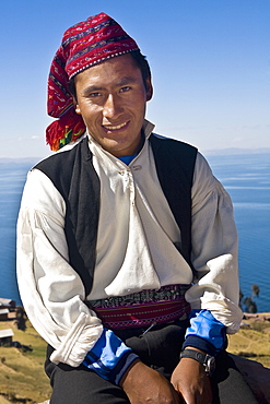 Portrait of a young man sitting and smiling, Taquile Island, Lake Titicaca, Puno, Peru