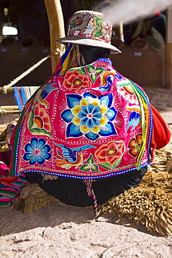 Rear view of a woman weaving in a loom, Aguanacancha, Peru