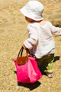 Rear view of a girl carrying a hand, Monteriggioni, Siena Province, Tuscany, Italy