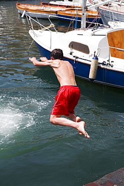 Rear view of a boy jumping in water, Borgo Marinaro, Bay of Naples, Naples, Naples Province, Campania, Italy