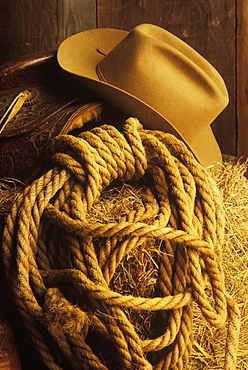 Close-up of a cowboy hat and lasso on hay