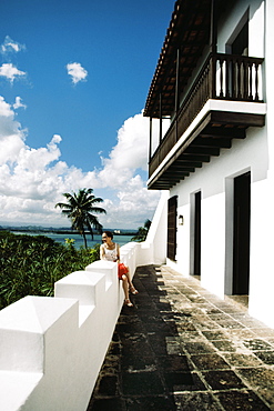 A woman is having a look over the dense trees from the balcony, San Juan, Puerto Rico