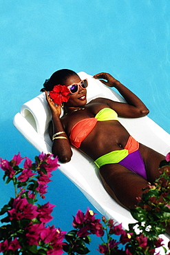 An African-American woman is floating on an inflatable mattress in a swimming pool, Destiny Villa, Jamaica