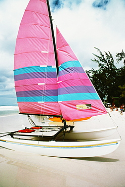 A boat with a colorful sail on a beach, Barbados