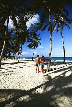 A couple on a holiday on a white sandy beach, Barbados