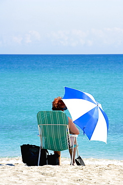 Rear view of a woman sitting on the beach, South Beach, Miami, Florida, USA