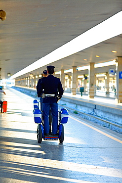 Rear view of two policemen traveling on scooters at a railroad station platform, Rome, Italy