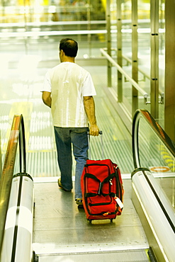 Rear view of a man walking and pulling luggage, Madrid, Spain