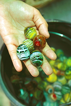 Close-up of a person's hand holding marbles
