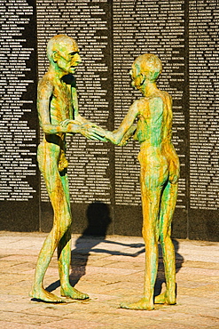 Two human sculptures in front of a wall