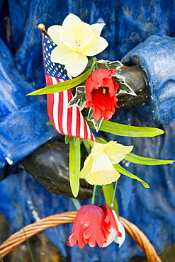 Close-up of an American flag and flowers in a statue's hand, USA