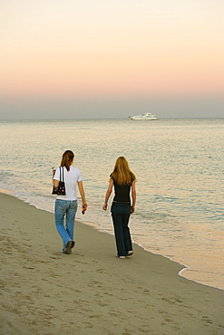 Rear view of two women walking on the beach