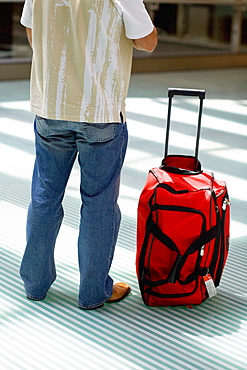 Rear view of a man standing with luggage beside him, Madrid, Spain