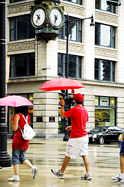 Side profile of pedestrians walking with umbrellas on a sidewalk, Chicago, Illinois, USA