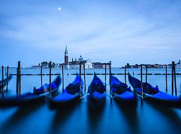 Venice lagoon, The Guideca viewed across the lagoon, gondolas moored, at night, moonlight.