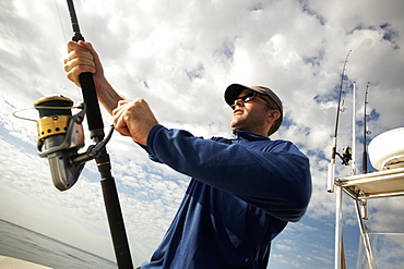 A man on a boat holding a fishing rod, USA