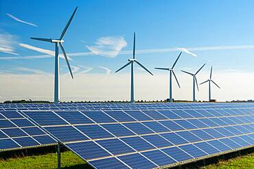 Wind turbine energy generators on wind farm, with solar panels underneath.