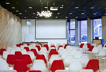 Large empty room with red and white chairs in rows