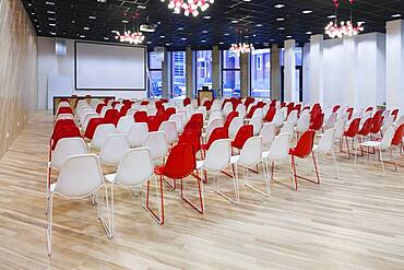 Large empty room with red and white chairs in rows