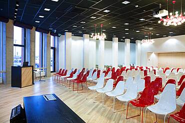 Large empty room with red and white chairs in rows