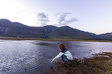 A boy exploring the shore of a lagoon in the shadow of the Kleinriver mountain range