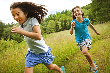 Two children, girls running and playing chase, laughing in the fresh air, New York state, USA