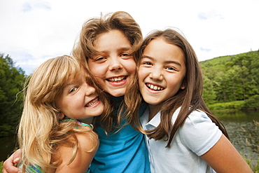 Three young girls, friends side by side, posing for a photograph in the open air, New York state, USA