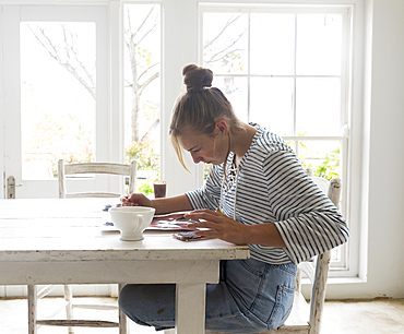 Teenage girl painting with watercolours in a light filled room