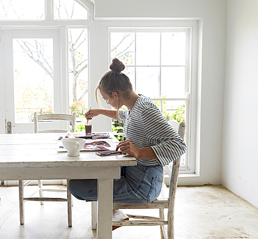 Teenage girl painting with watercolours in a light filled room