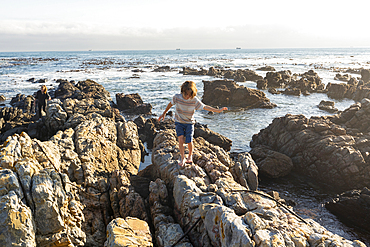 Young boy climbing over and exploring the rocks and pools