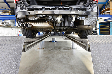 Car under repair on a service ramp or lift in an auto repair workshop.