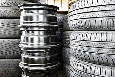 Stack of car tyres and wheel rims in an auto repair shop garage.