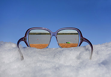 Beach and lakeside seen in reflection in sunglasses on thick snow.