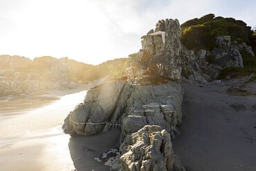 Two children climbing the rocks above a sandy beach, Grotto Beach, Western Cape, South Africa