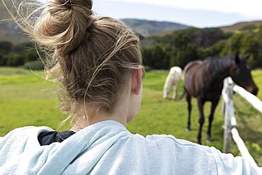 Teenage girl watching horses in a field, Stanford, Western Cape, South Africa