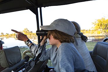 Boy in a safari jeep looking through binoculars, Okavango Delta, Botswana