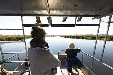 A family relaxing on a motorboat on a waterway, Okavango Delta, Botswana