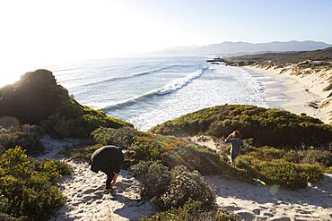 A teenager and her brother on a path down to a sandy beach, Walker Bay Nature Reserve, South Africa