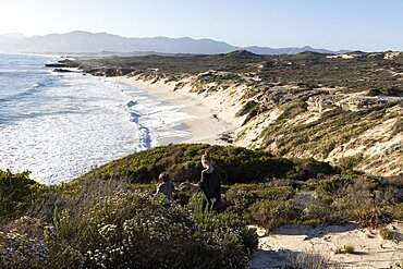 A teenager and her brother on a path down to a sandy beach, Walker Bay Nature Reserve, South Africa