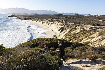 A teenager and her brother on a path down to a sandy beach, Walker Bay Nature Reserve, South Africa