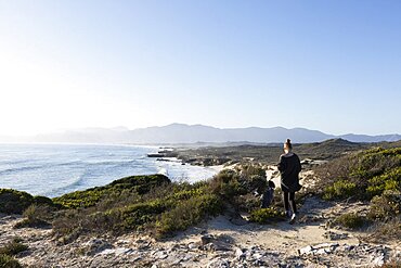 A teenager and her brother on a path down to a sandy beach, Walker Bay Nature Reserve, South Africa