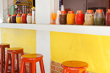 Bar stools, and rows of juice bottles, market stall and drinks stand