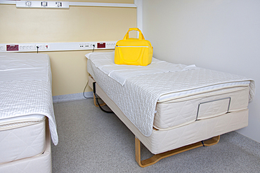 Two patient beds in a maternity unit, a bright yellow bag.