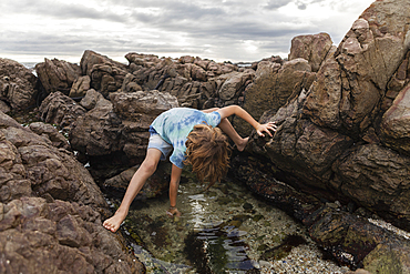 Young boy exploring tidal pool, De Kelders, Western Cape, South Africa.