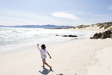 Eight year old boy exploring a sandy beach.