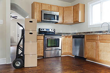 Moving house, relocation, cardboard boxes piled up in a house fitted kitchen