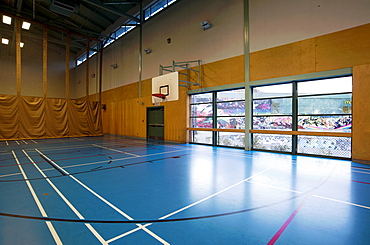 Spacious gymnasium with a basketball court floor markings, light and airy, glass doors