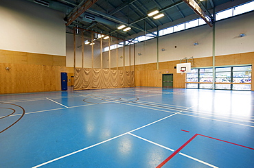 Spacious gymnasium with a basketball court floor markings, light and airy, glass doors