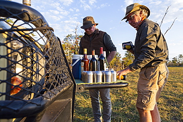 People enjoying a sundowner, drinks at sunset on a safari drive, Okavango Delta, Botswana