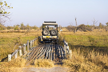A safari vehicle crossing a bridge in the landscape of swamps and waterways, Okavango Delta, Botswana